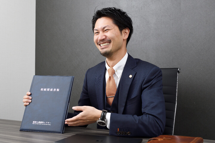 相続専門の税理士事務所レクサー代表税理士伊東秀明が相続関係書類を見せて笑う写真